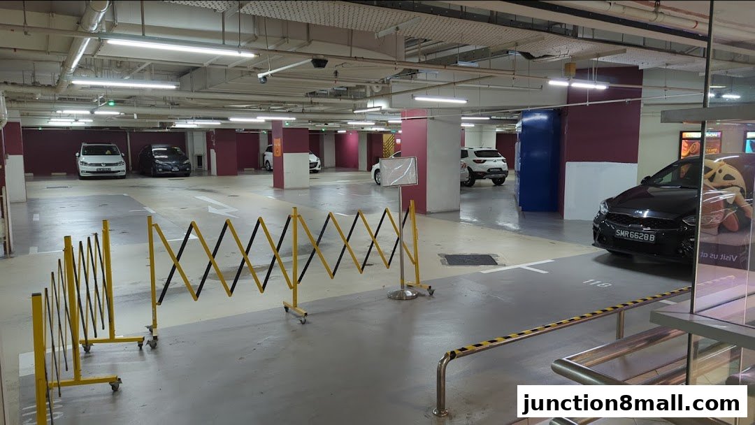 A parking lot with cars, barriers, and pillars, indicating a shopping mall's parking facility.