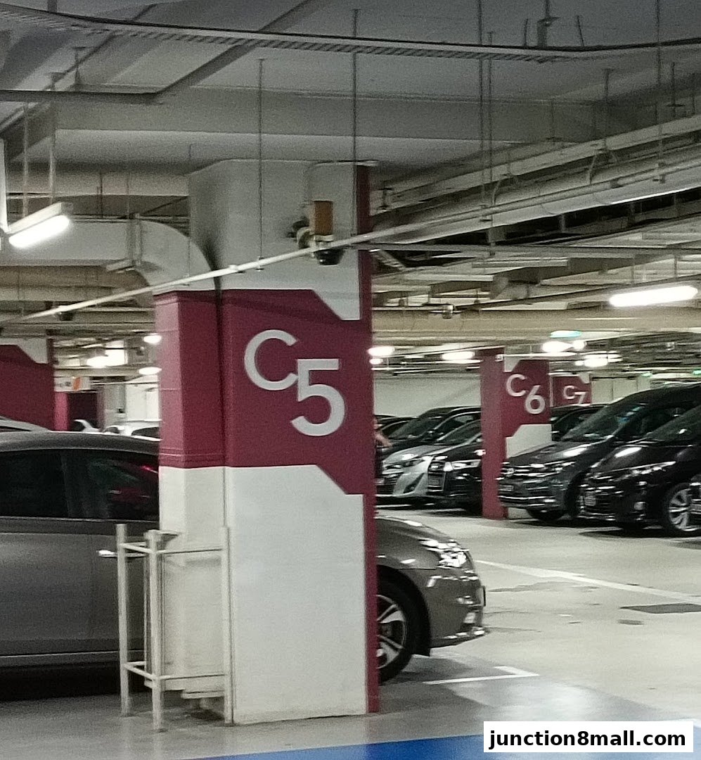 A parking garage with cars parked and signs indicating parking sections.