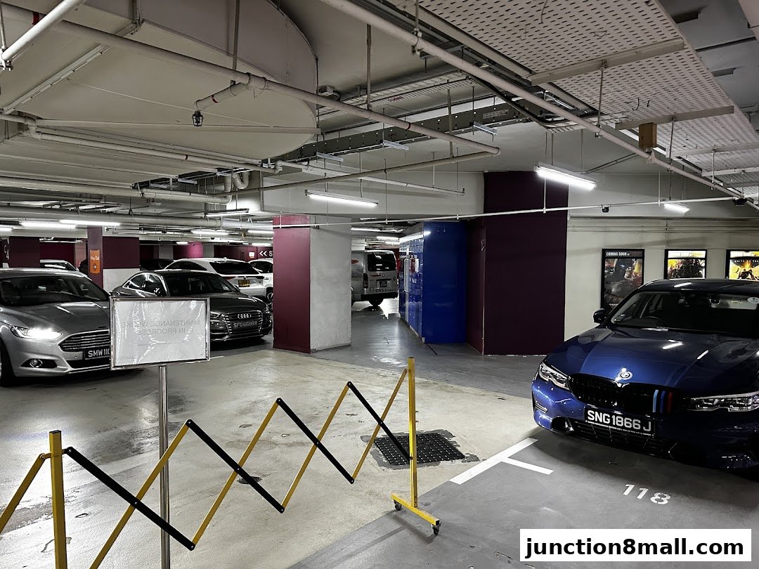 A parking lot with several cars, including a blue BMW and a silver Audi, and a maintenance sign.
