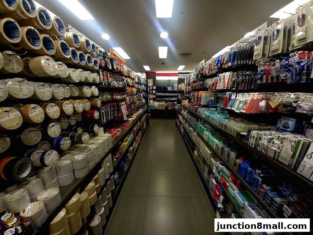 A wide aisle in a POPULAR Bookstore, showcasing shelves stocked with stationery and tapes.