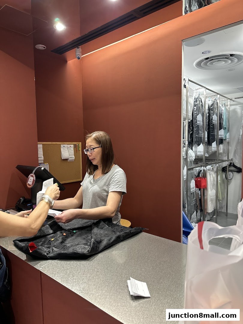 A dry cleaner employee hands a receipt to a customer at the counter.