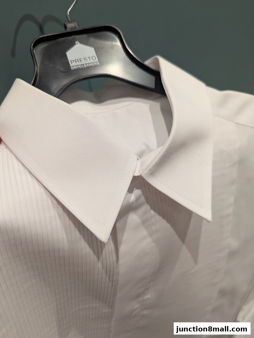 A crisp white dress shirt with a pleated front, displayed on a hanger.