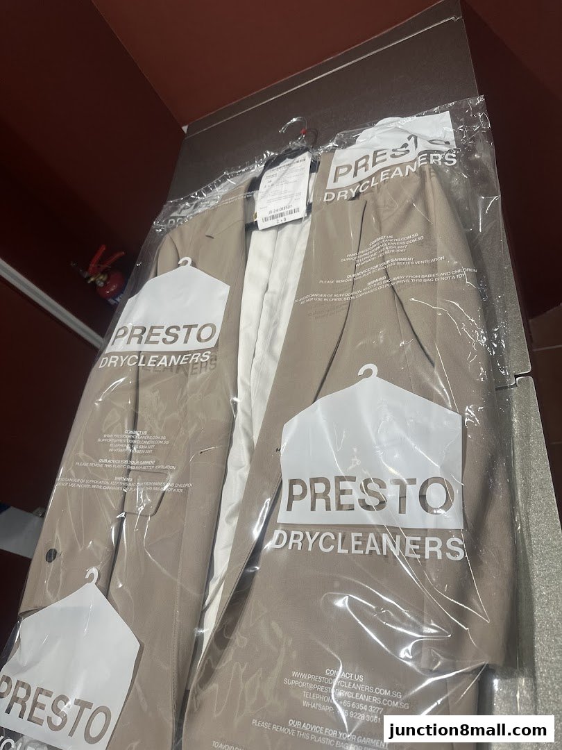 A suit is neatly packaged in plastic bags with the Presto Drycleaners logo.