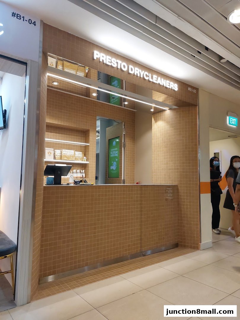 The clean and modern storefront of Presto Drycleaners, featuring a tiled counter and shelves with branded products.