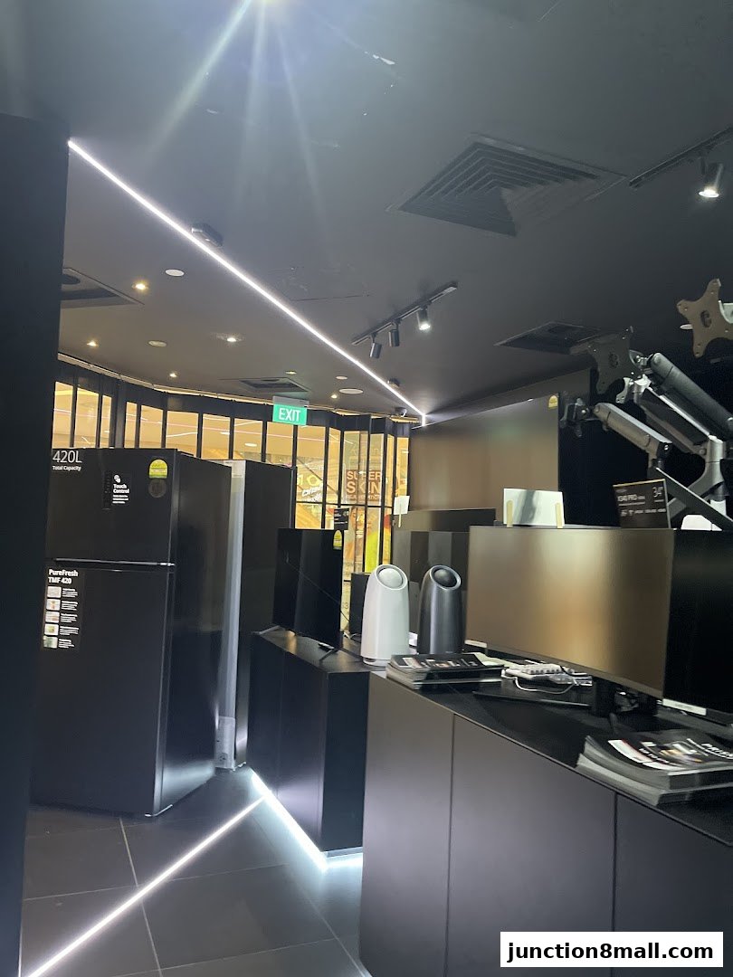 Interior view of a modern electronics store with refrigerators, monitors, and sleek displays.