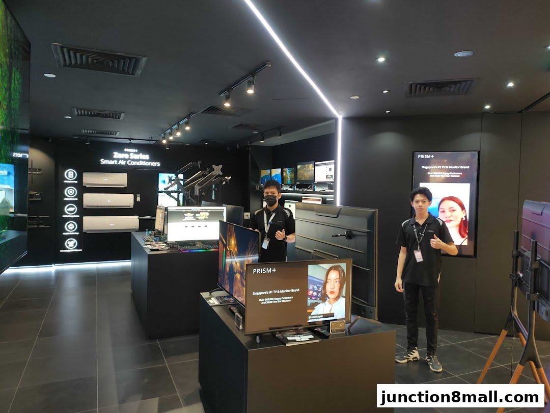 Two staff members stand in a modern electronics store showcasing air conditioners and TVs.