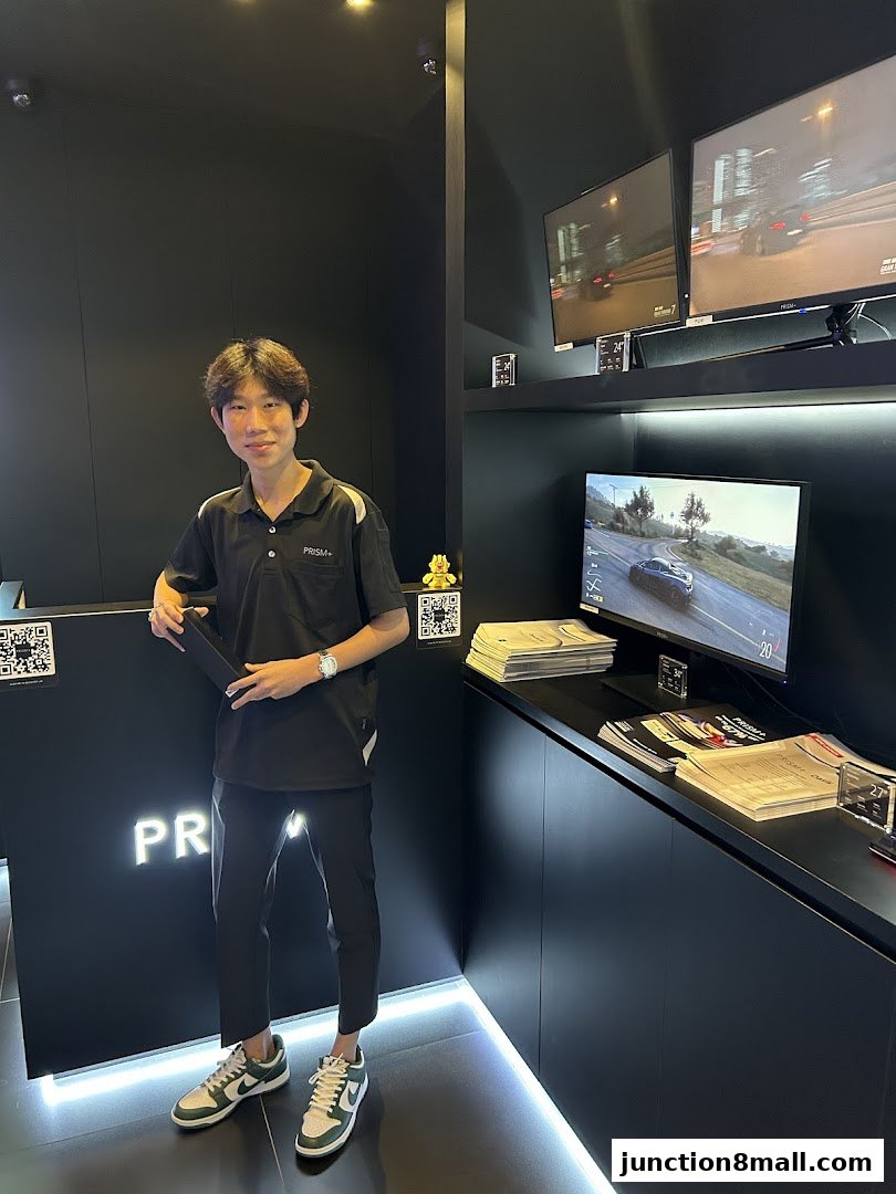 A young man stands in a modern retail store with multiple screens displaying car racing games.