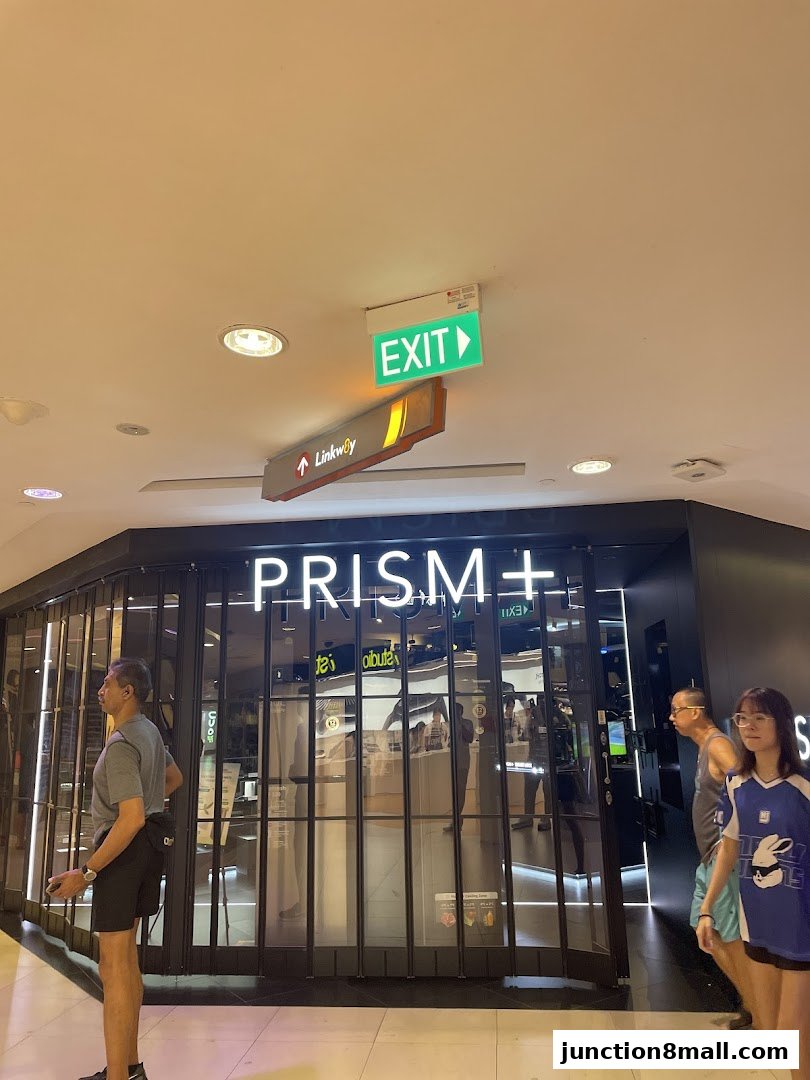 The PRISM+ store entrance with a closed gate and people walking by.