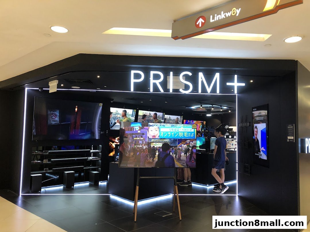 The PRISM+ store front displays various screens and soundbars, with a person standing inside.