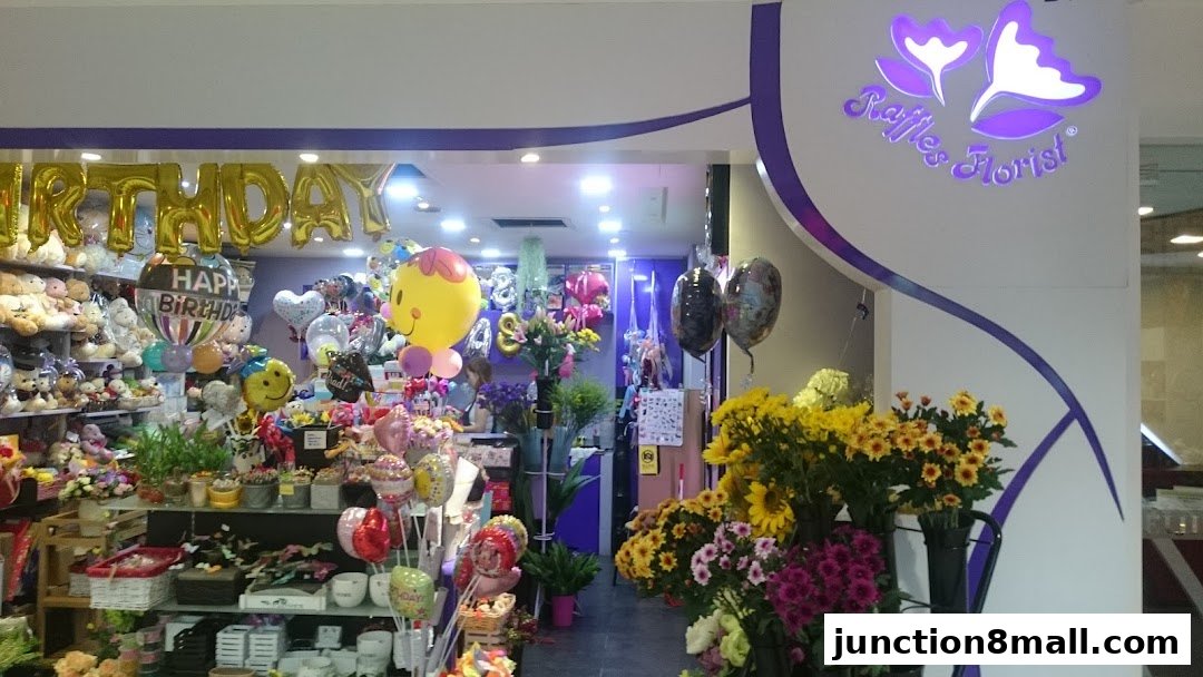 A florist shop entrance filled with balloons, stuffed animals, and a vibrant display of fresh flowers.