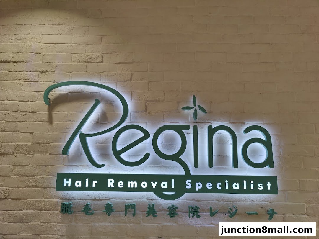 A glowing sign for Regina Hair Removal Specialist on a brick wall.