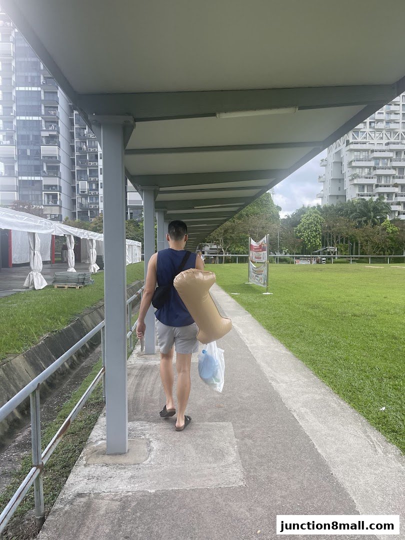 A person walks down a covered walkway carrying an inflatable and shopping bags.