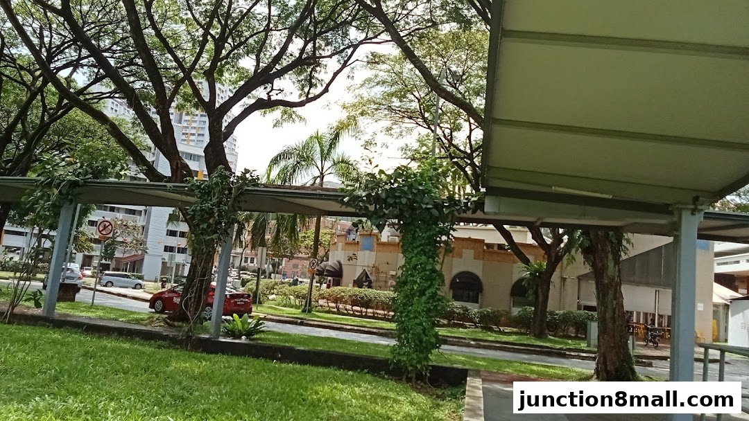 A view of a building with arched windows and greenery, seen from a covered walkway.