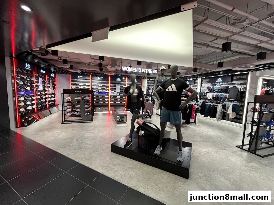 Interior of a modern sports apparel store with mannequins and shelves of shoes and clothing.