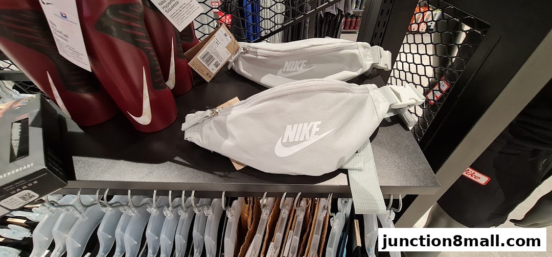 Nike waist bags and sports accessories displayed on shelves and hangers.