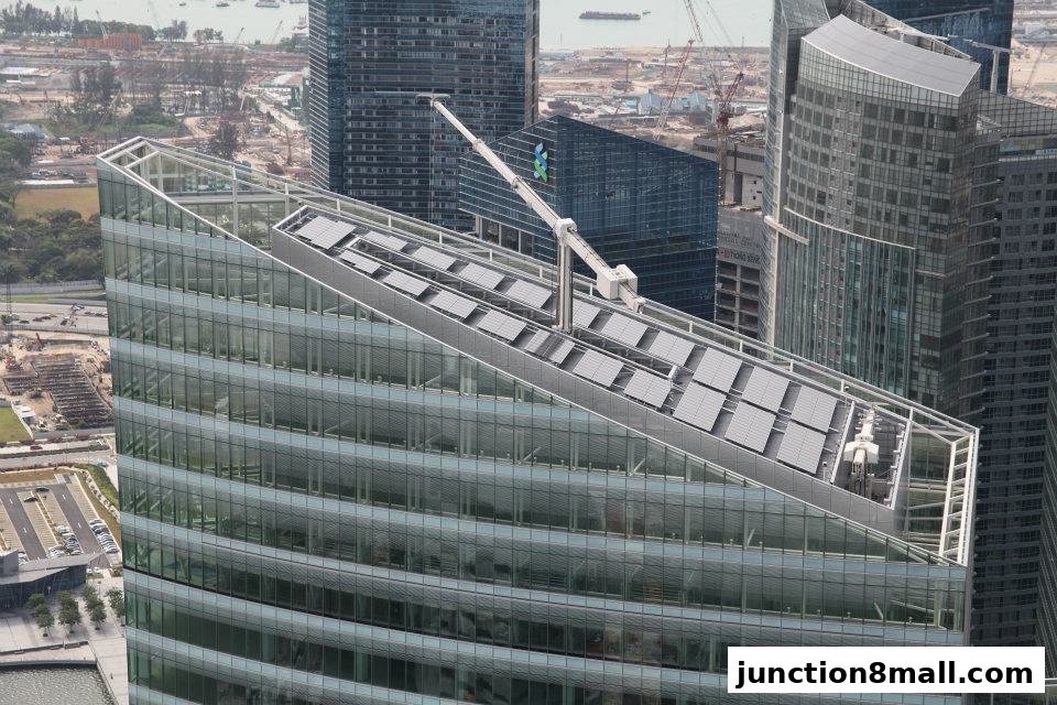 An aerial view of a modern skyscraper with solar panels on its angled roof.