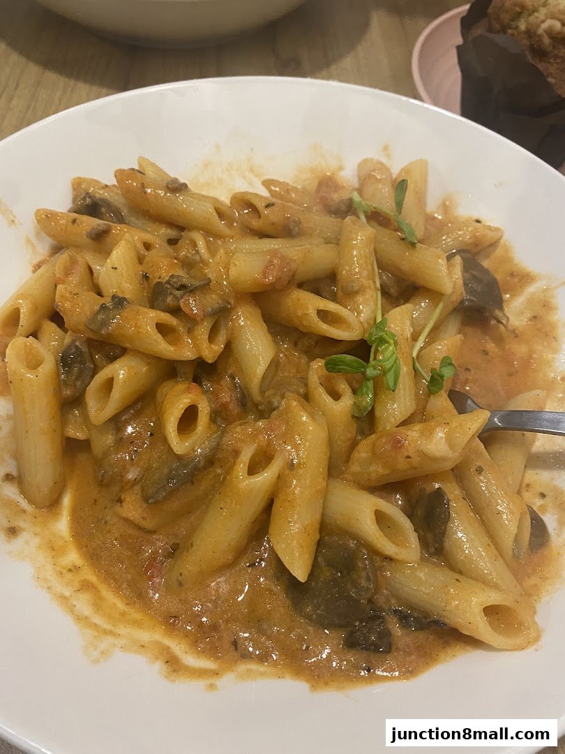 A close-up shot of a creamy pasta dish with mushrooms and a garnish of microgreens.