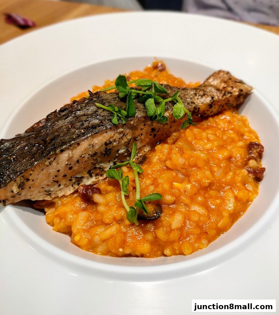 A close-up of a delicious salmon dish with creamy risotto, garnished with fresh greens.