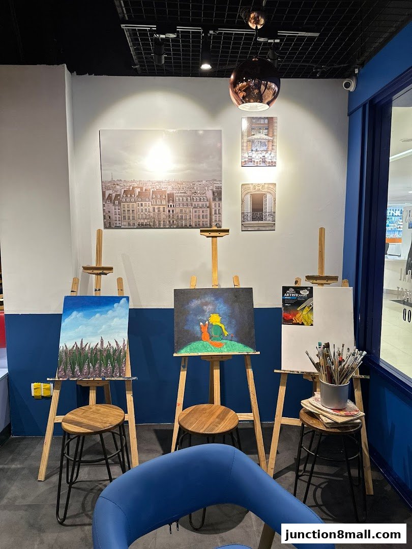 An art studio setup with easels, paintings, art supplies, and seating.