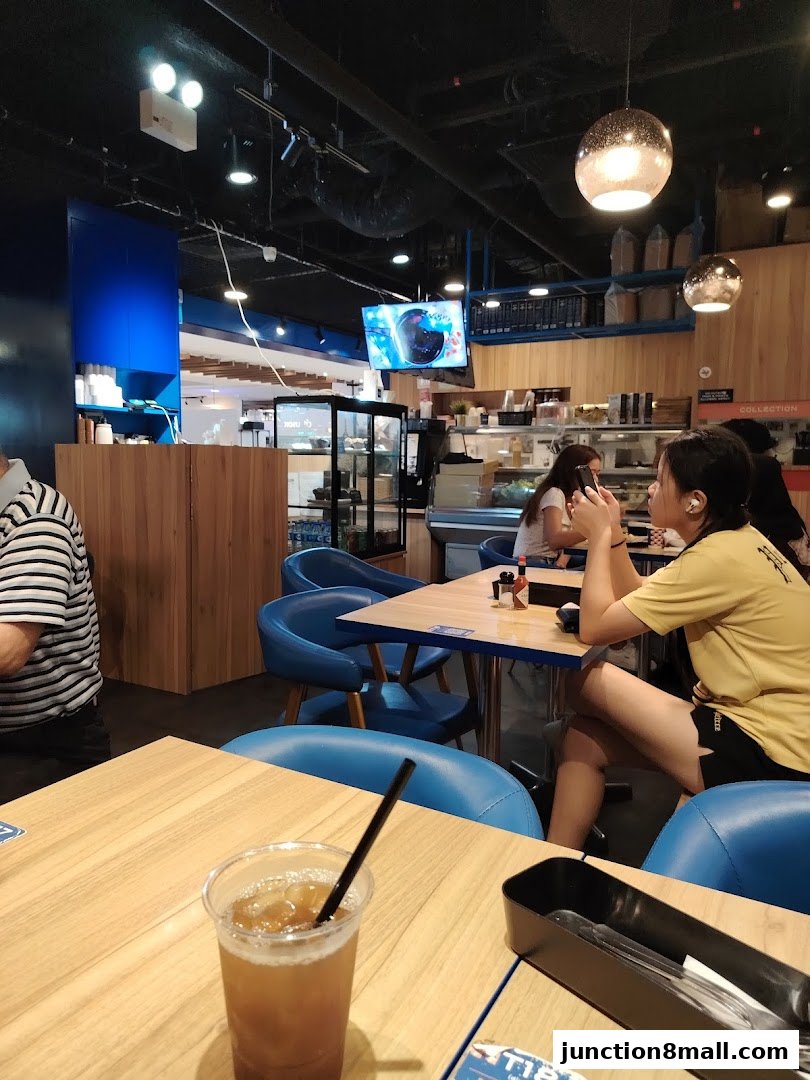 Interior of a cafe with customers seated at tables and a drink in the foreground.