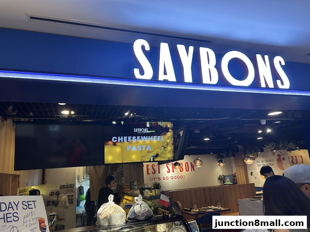 The Saybons restaurant storefront with illuminated signage and a digital display advertising pasta.