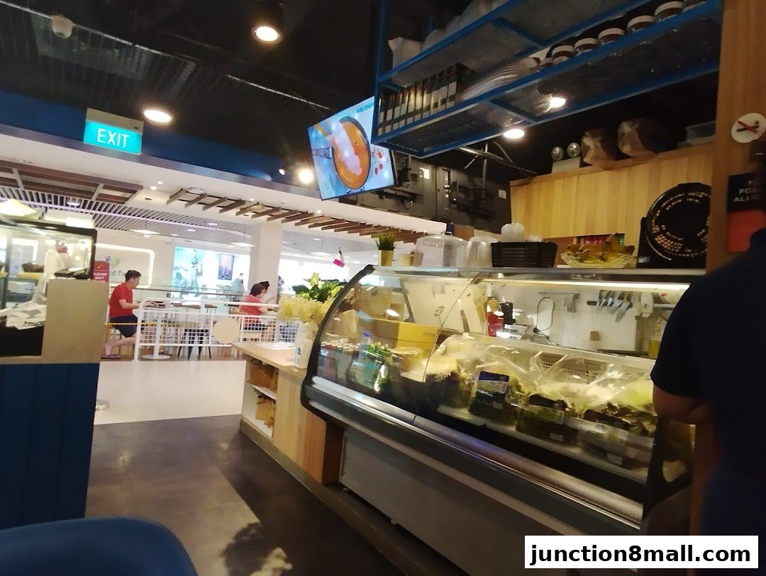 Interior view of a food establishment with a display fridge and seating area.