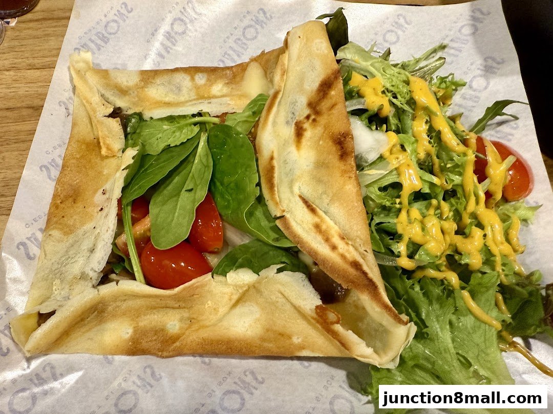 A savory crepe filled with greens and tomatoes, served with a side salad.