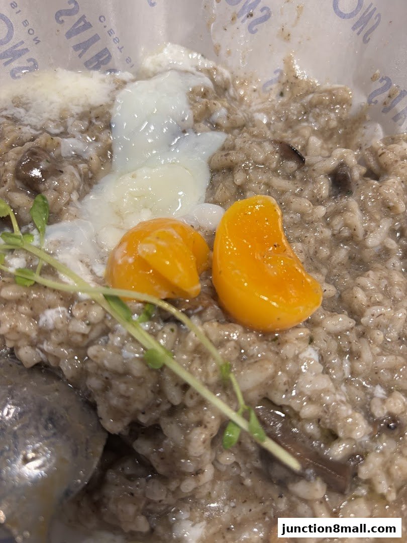 A close-up of a creamy mushroom risotto topped with a poached egg and garnished with microgreens.