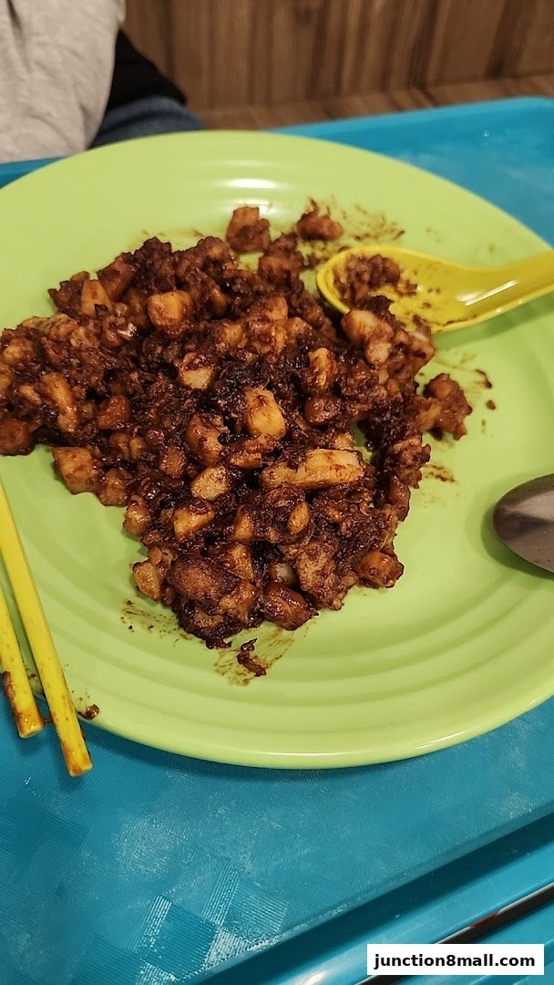 A plate of savory fried radish cake with chopsticks and a spoon.