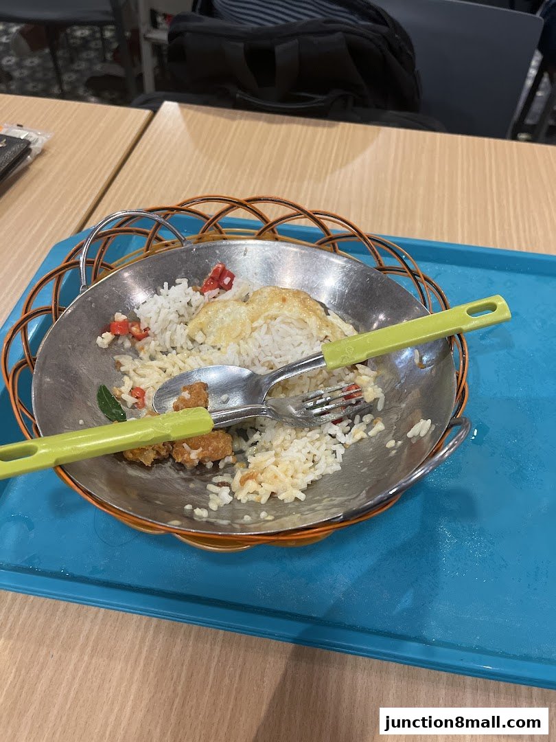 A partially eaten meal of rice and fried chicken served in a metal bowl on a blue tray.