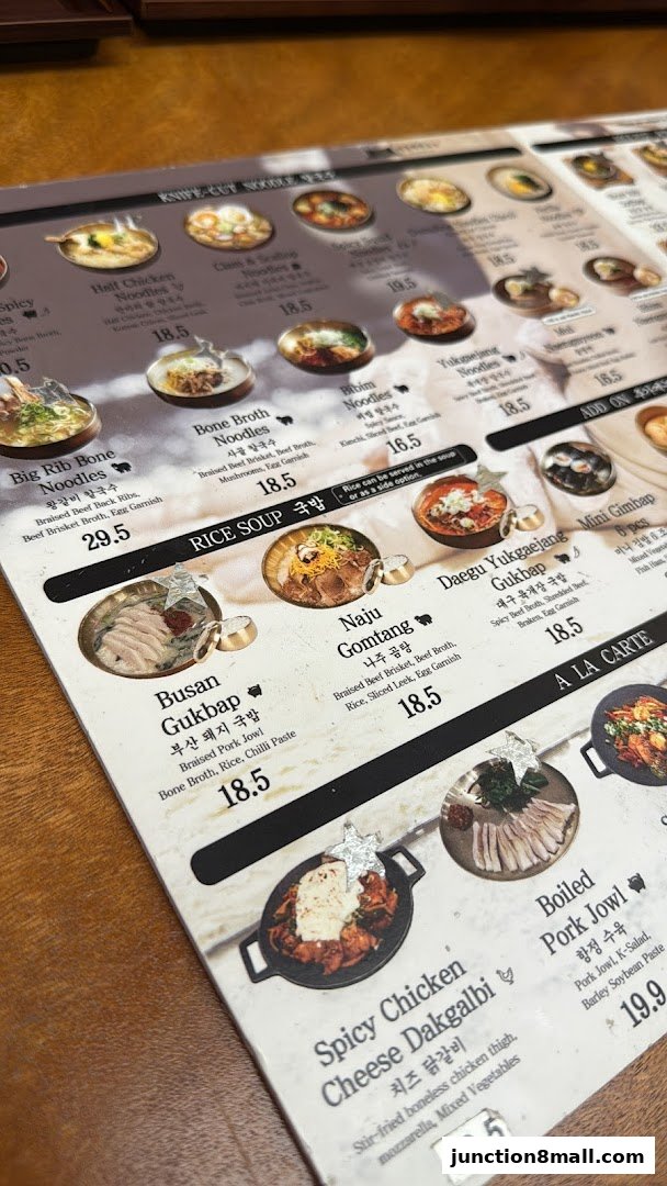 A close-up view of a Korean noodle shop menu featuring various noodle dishes and rice soups.