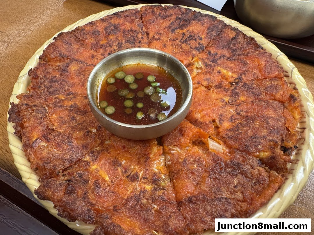 A close-up shot of a savory Korean pancake with a dipping sauce.