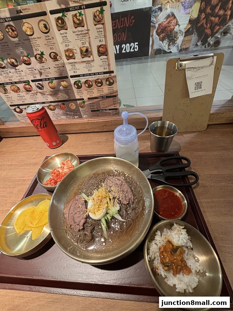 A table setting at Seoul Noodle Shop with a bowl of noodles, rice, kimchi, and a can of Coca-Cola.