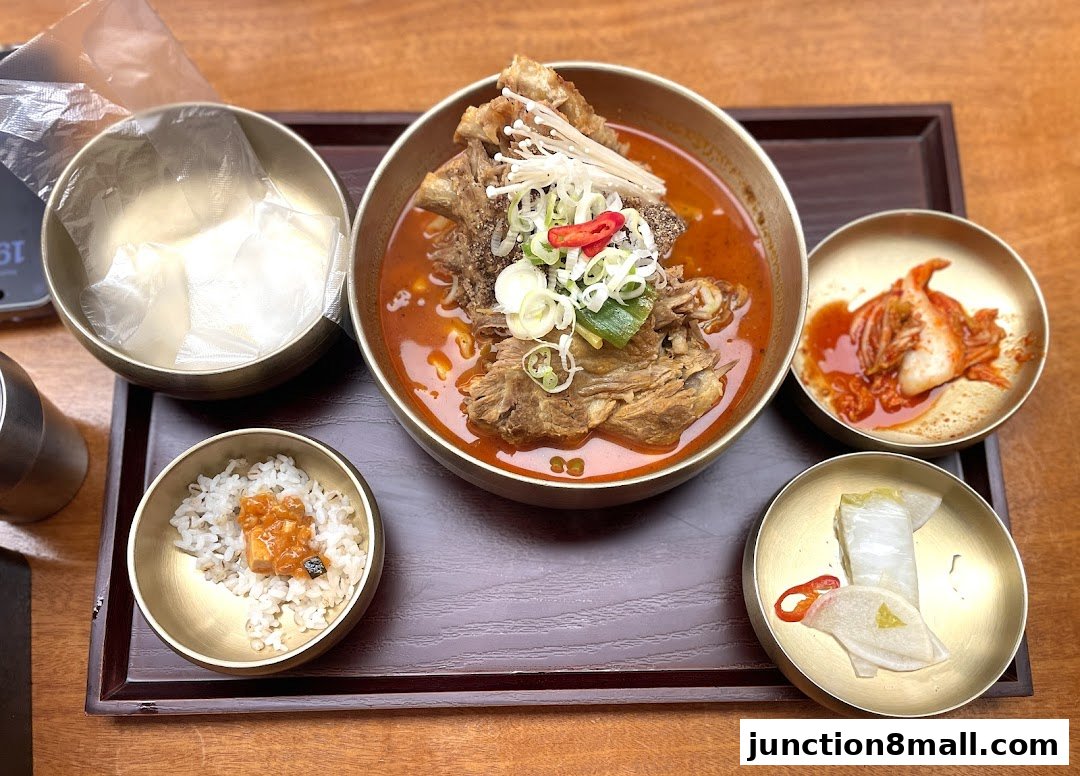 A steaming bowl of Korean gamjatang with rice and side dishes.