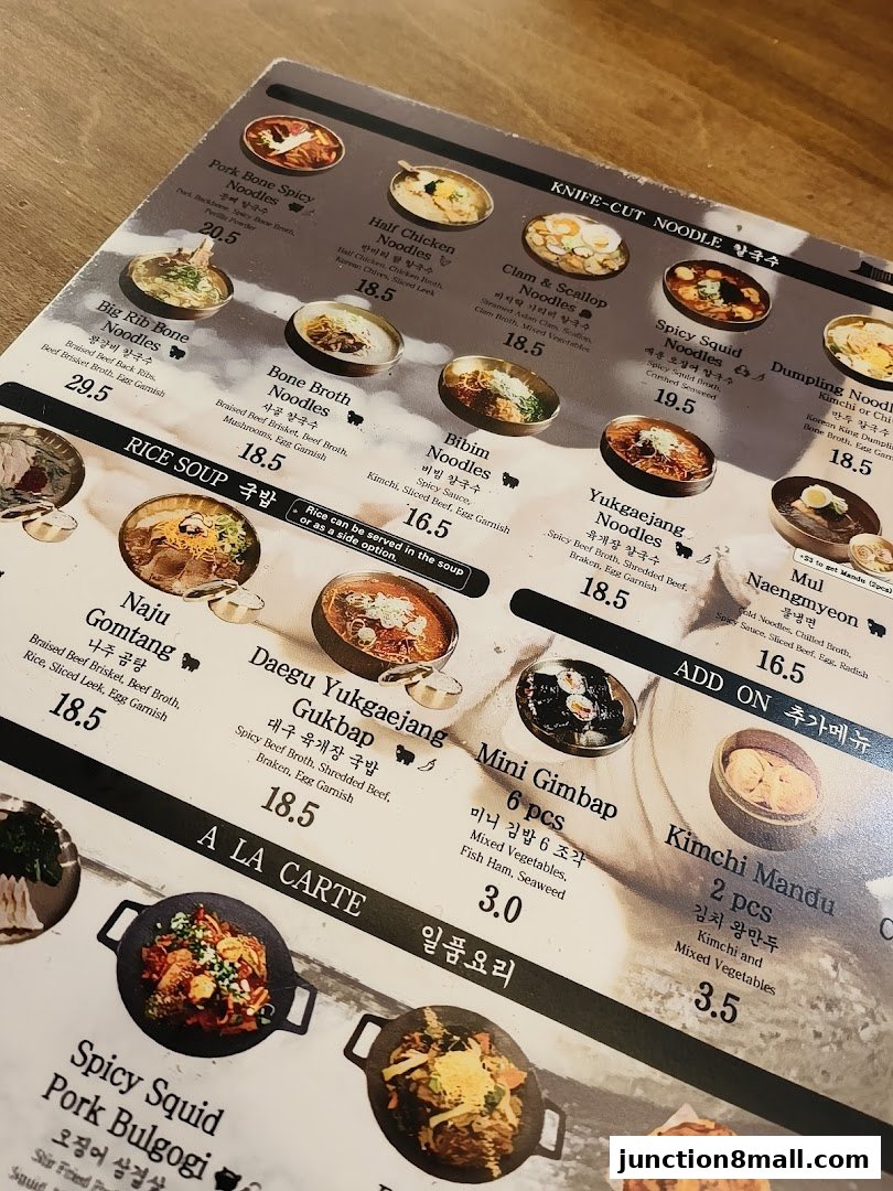 A close-up view of a Korean noodle shop menu with various noodle dishes and prices.