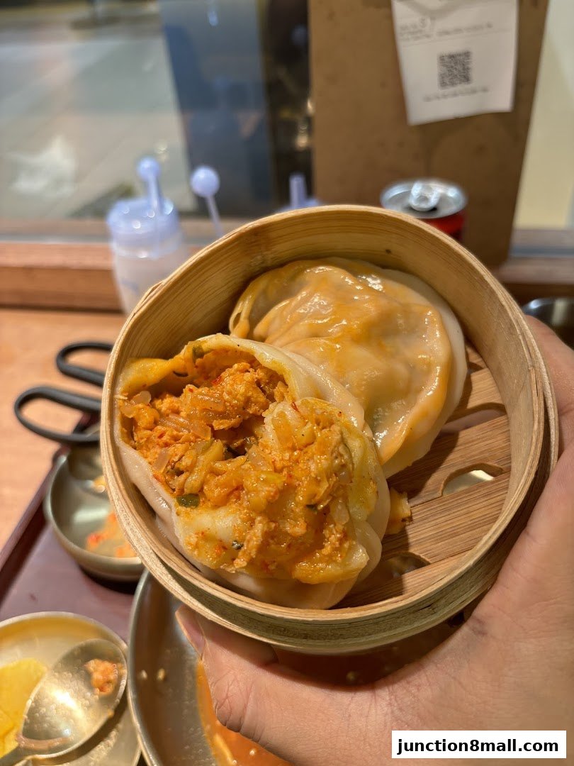 A close-up shot of steaming kimchi dumplings served in a bamboo steamer.