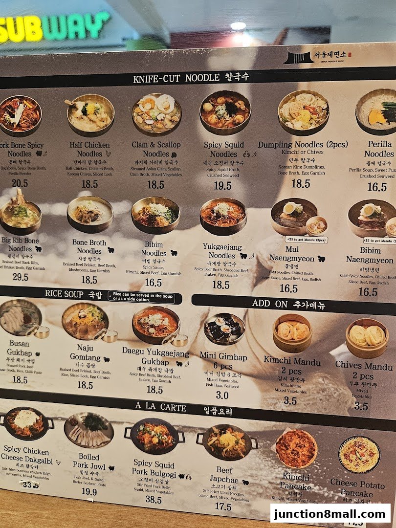 A menu board displaying various Korean noodle dishes, rice soups, and side dishes with prices.