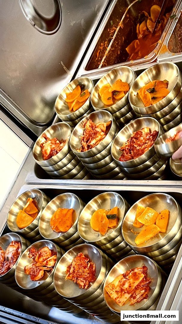 A close-up of various Korean side dishes, including kimchi and pickled vegetables, served in small metal bowls.