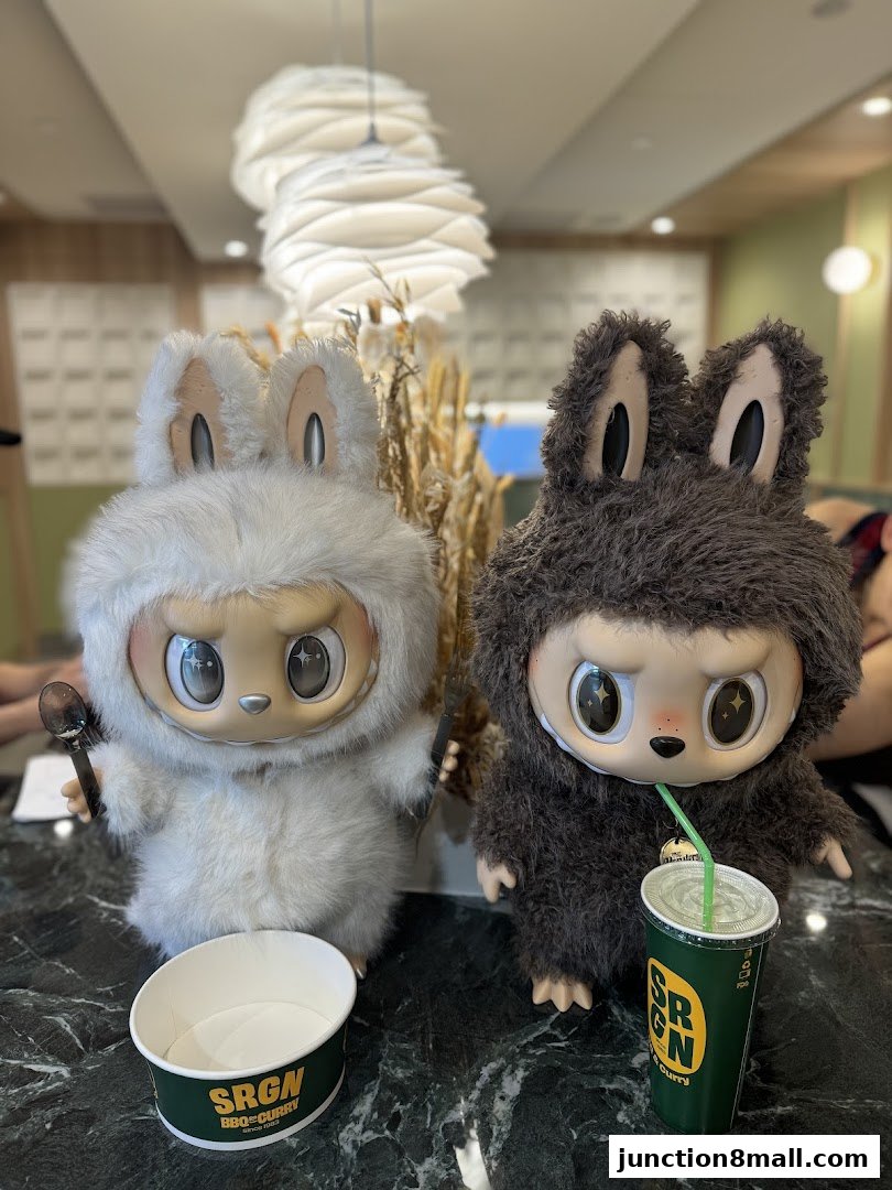 Two fluffy characters, one white and one dark brown, sit with a cup and bowl.