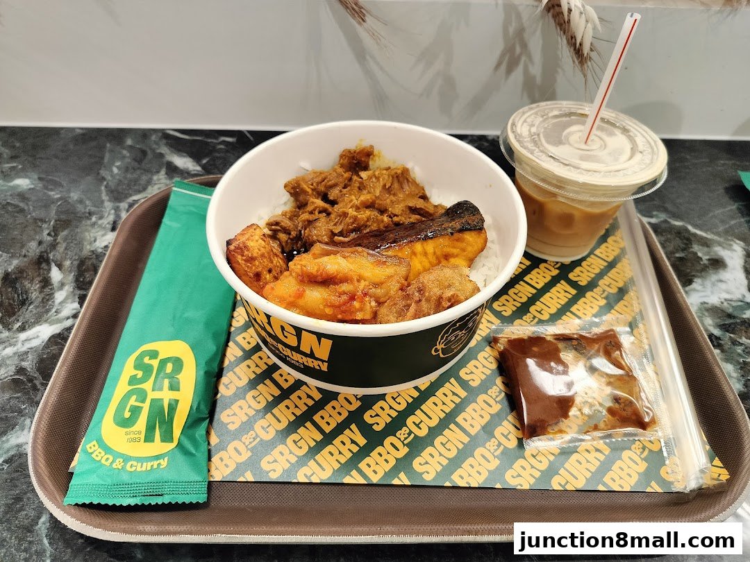 A tray with a bowl of rice topped with meat and fish, a drink, and a packet of sauce.