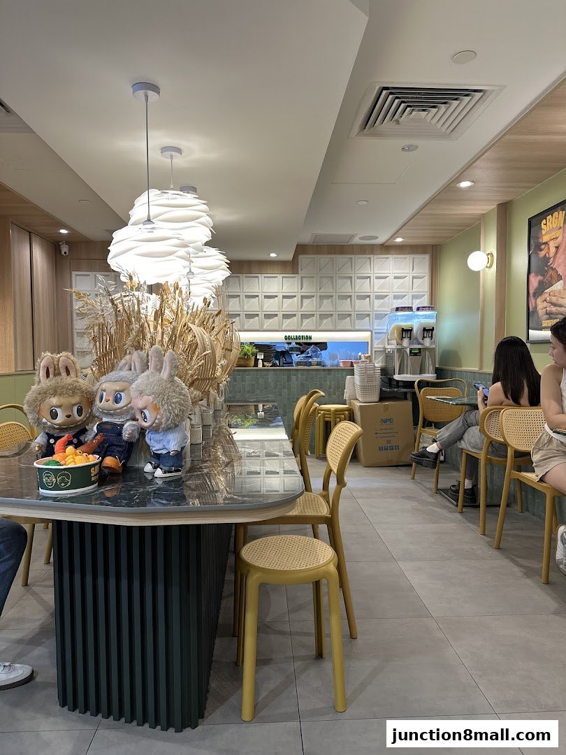 Interior of a modern cafe with plush toys on a table and people seated.