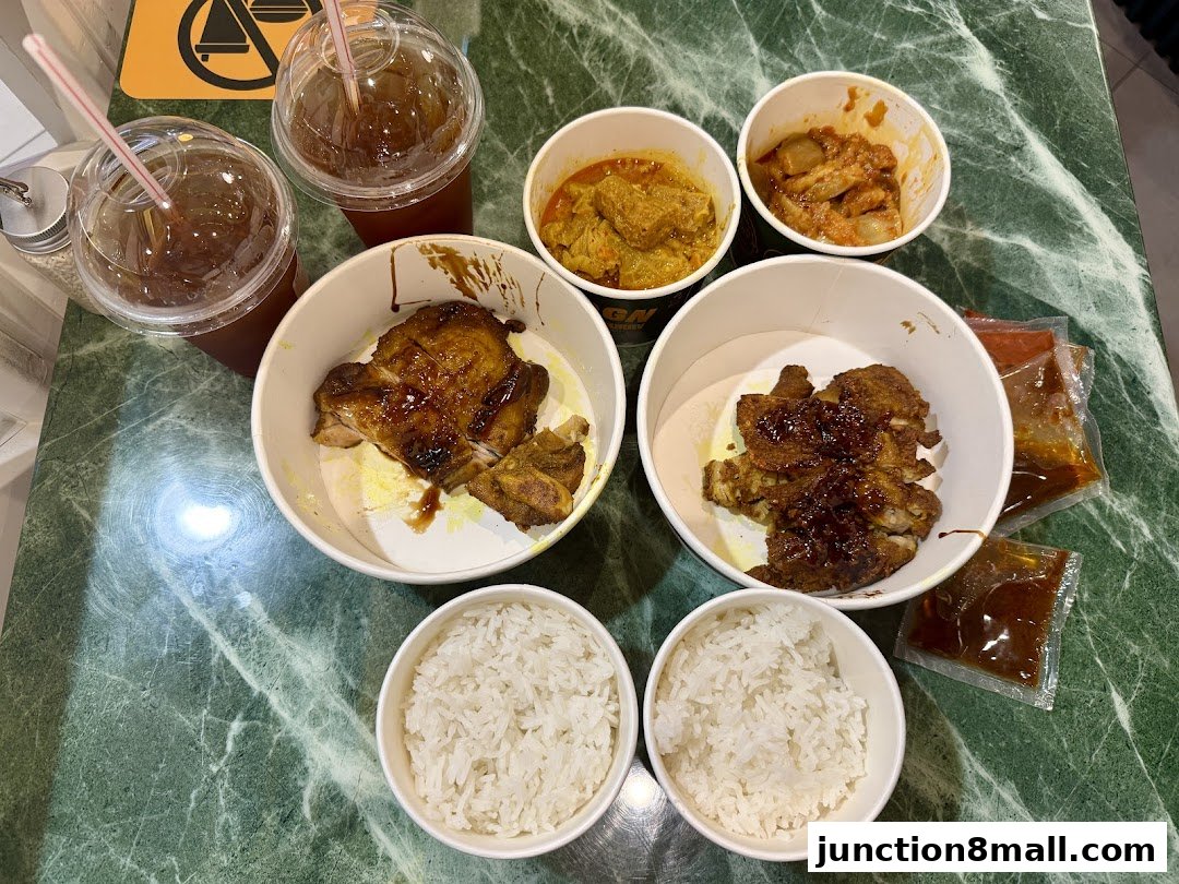 A spread of takeaway food including rice, chicken dishes, curry, and drinks.