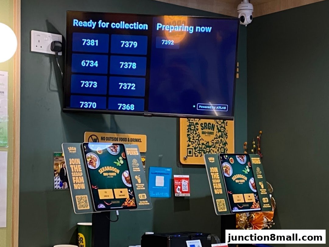 A digital display shows order numbers, with self-order kiosks and promotional materials.