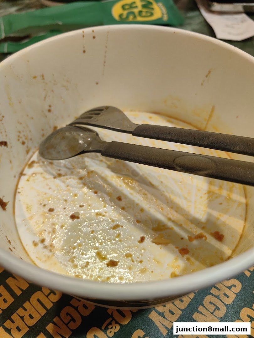 A used bowl with leftover curry sauce and cutlery, with the shop's branding visible.