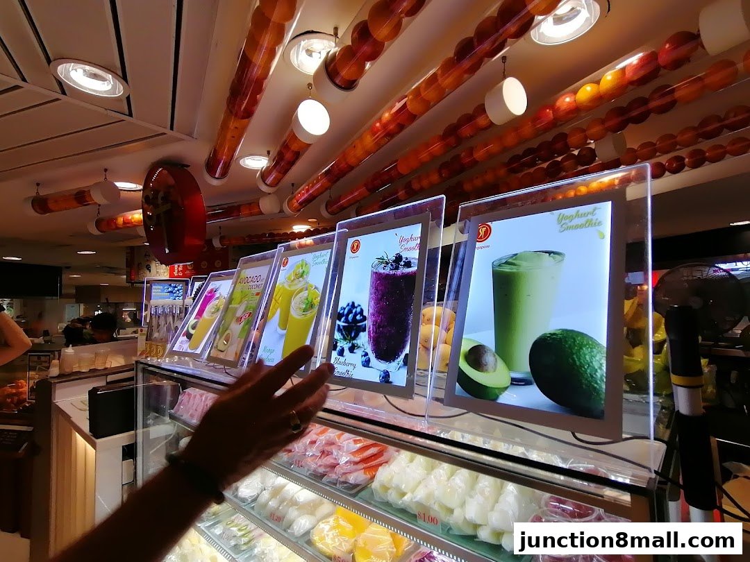 A display of colorful fruit smoothies and fresh fruits at a juice bar.