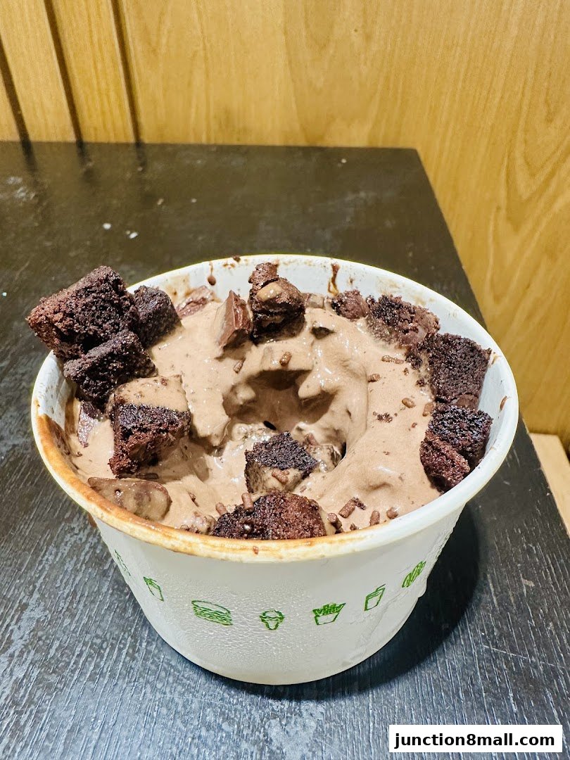 A bowl of chocolate ice cream topped with brownie pieces and chocolate chunks.
