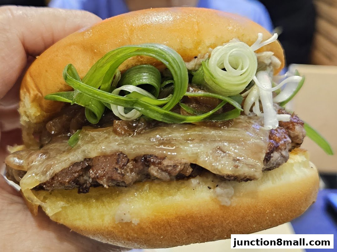 A close-up shot of a delicious burger with melted cheese and green onions.