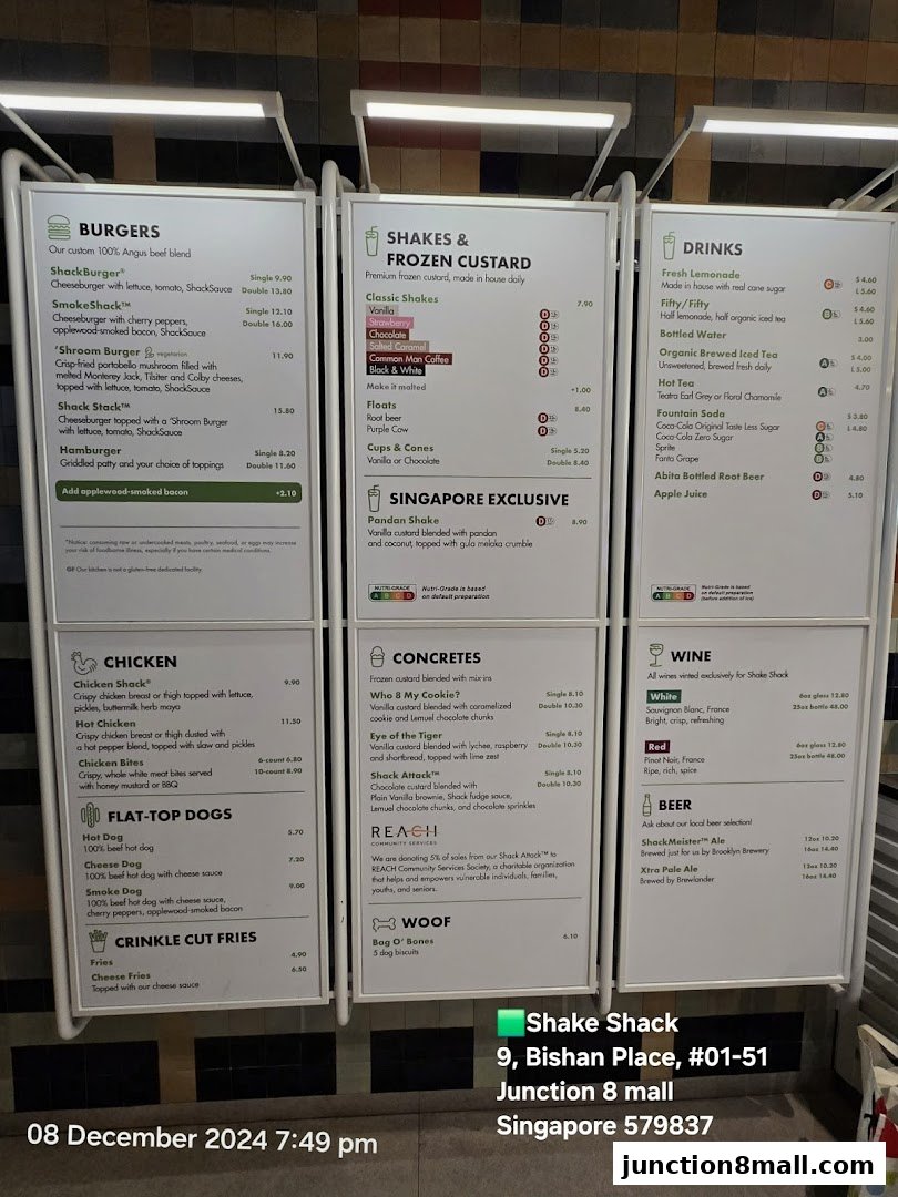 A menu board for Shake Shack Junction 8, displaying burgers, shakes, drinks, chicken, hot dogs, concretes, and wine.