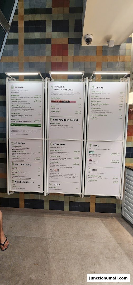 A menu board displaying burgers, shakes, drinks, chicken, hot dogs, fries, concretes, wine, and beer.