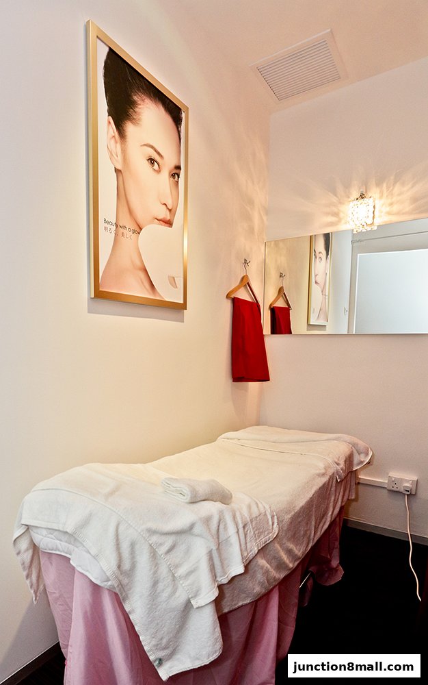 A treatment bed with towels and a beauty advertisement on the wall.
